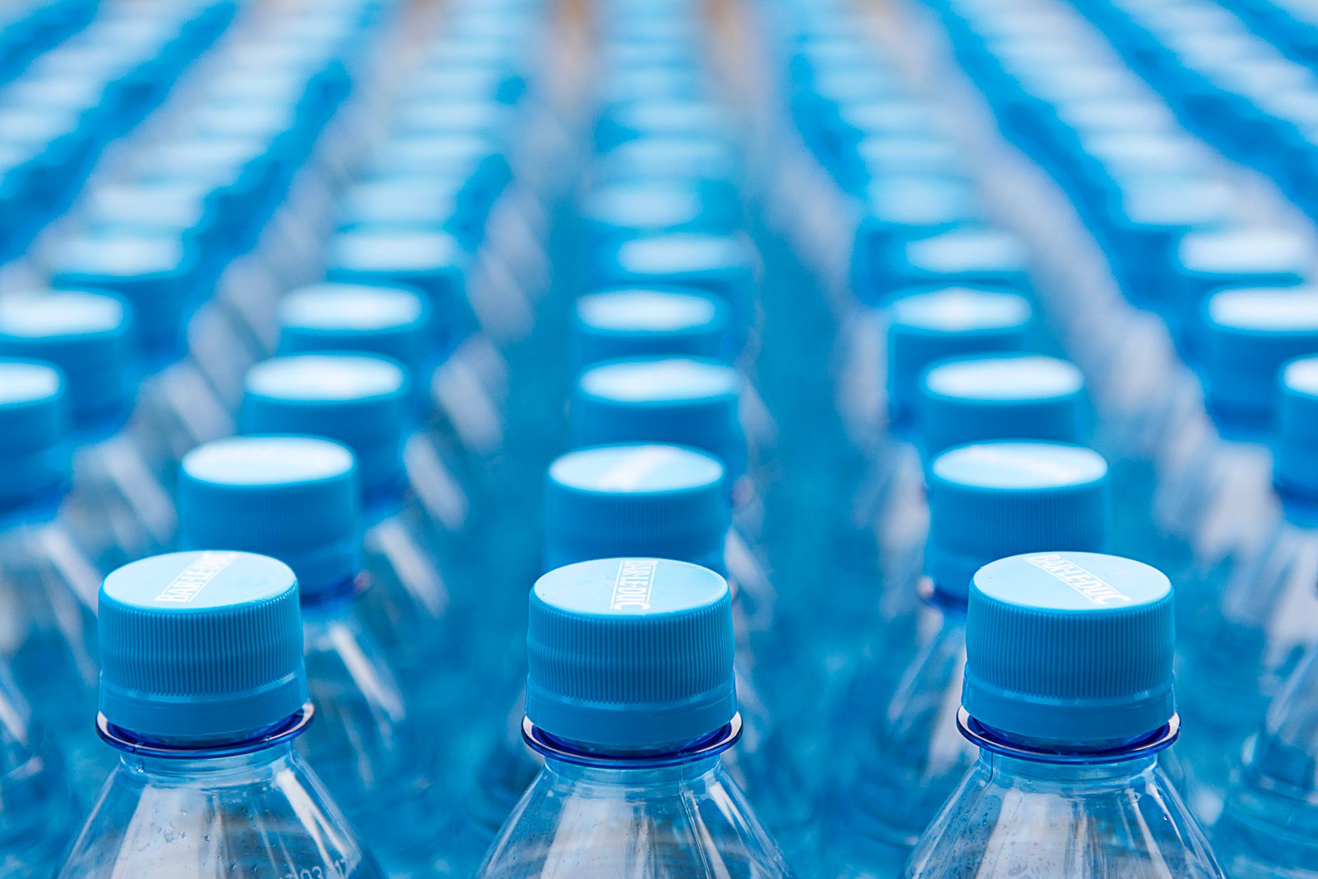 Rows of pale blue plastic bottle closures on a filling line