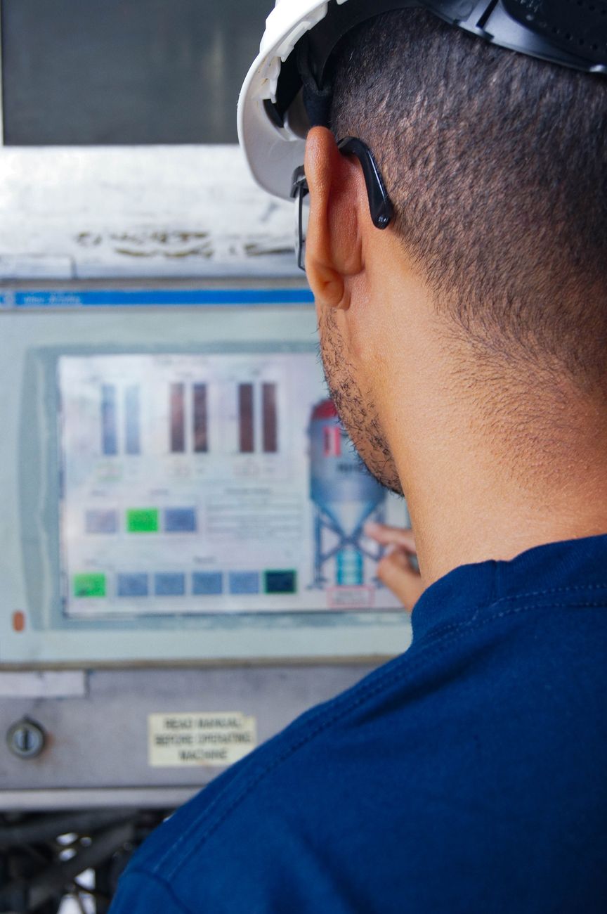 An engineer in a hard hat reading a machine control screen